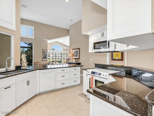 kitchen featuring sink, dark stone countertops, white cabinets, light tile patterned floors, and white appliances