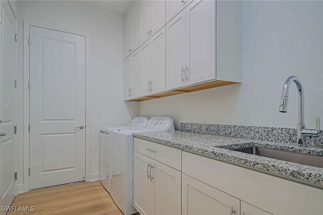 laundry area featuring sink, cabinets, independent washer and dryer, and light wood-type flooring