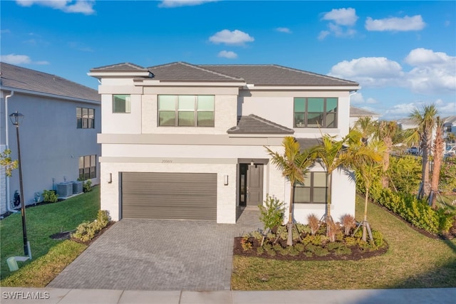 view of front of property with a garage, central AC unit, and a front lawn