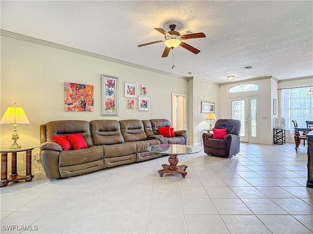 tiled living room featuring ceiling fan, crown molding, french doors, and a textured ceiling