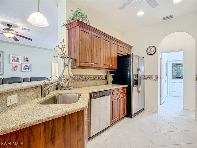 kitchen featuring sink, hanging light fixtures, ceiling fan, stainless steel appliances, and light stone countertops