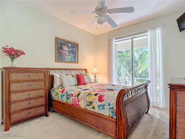 bedroom featuring ceiling fan, light colored carpet, and a textured ceiling