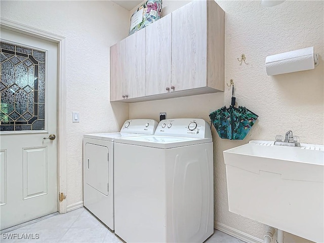 laundry room featuring washer and dryer, sink, cabinets, and light tile patterned flooring