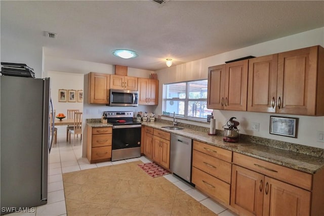 kitchen featuring stainless steel appliances, sink, and light tile patterned floors