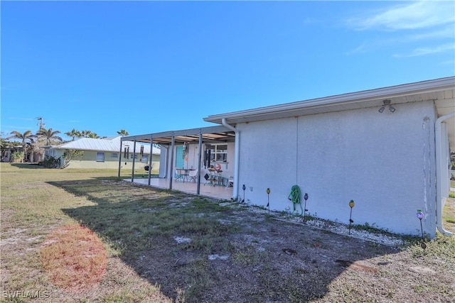 view of side of property with a patio and a lawn