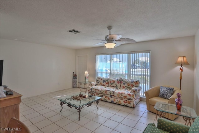 living room featuring light tile patterned flooring, ceiling fan, and a textured ceiling