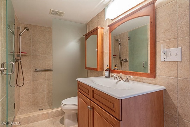 bathroom with a shower with door, vanity, tile patterned flooring, and toilet