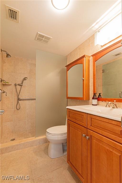 bathroom with vanity, tile patterned floors, toilet, and tiled shower