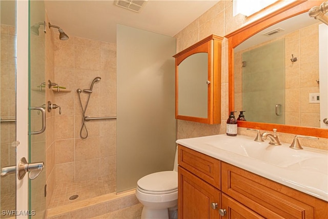 bathroom featuring vanity, a shower with shower door, and toilet