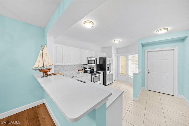 kitchen with backsplash, stainless steel appliances, kitchen peninsula, and white cabinets