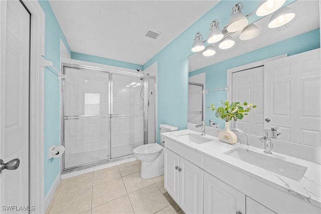 bathroom featuring a shower with door, vanity, tile patterned floors, and toilet