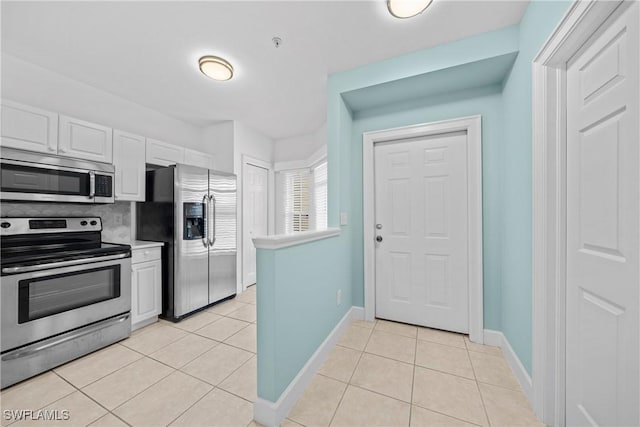 kitchen with white cabinetry, appliances with stainless steel finishes, light tile patterned flooring, and backsplash