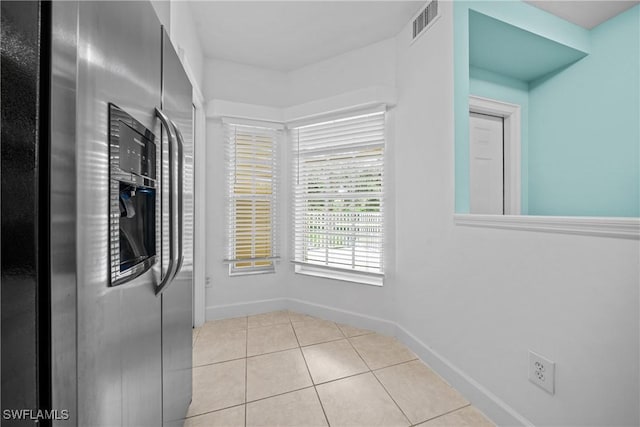 kitchen featuring light tile patterned flooring and stainless steel refrigerator with ice dispenser