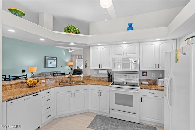 kitchen with sink, white appliances, white cabinets, and stone countertops