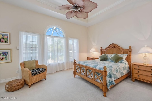 carpeted bedroom featuring ornamental molding, a raised ceiling, a ceiling fan, and baseboards