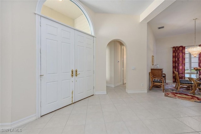 foyer with visible vents, arched walkways, baseboards, an inviting chandelier, and light tile patterned flooring