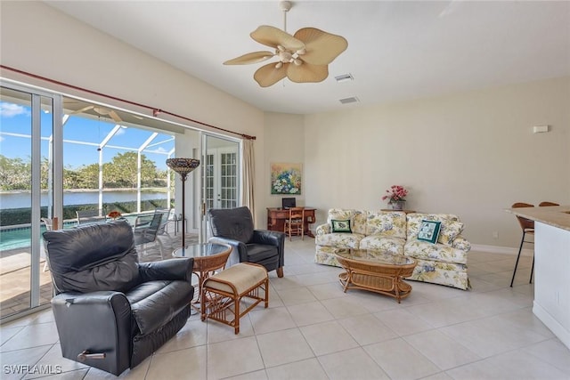 living area featuring a water view, a sunroom, light tile patterned floors, and a ceiling fan