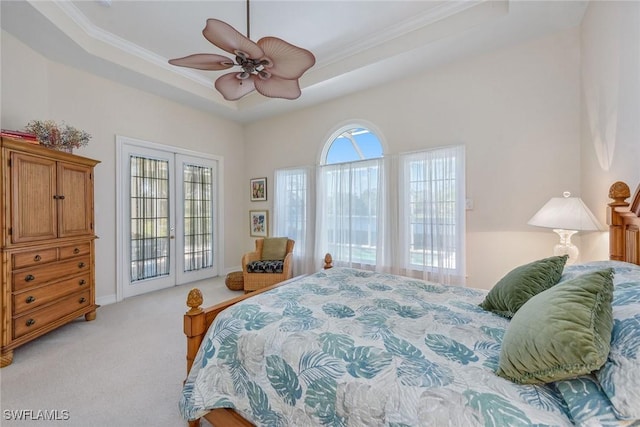 bedroom featuring light carpet, access to exterior, a tray ceiling, crown molding, and french doors