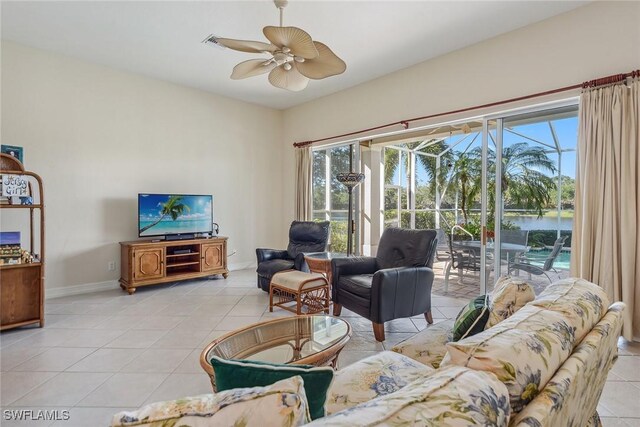 living room with light tile patterned floors, baseboards, ceiling fan, and a healthy amount of sunlight