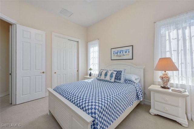 bedroom featuring baseboards, light carpet, and a closet