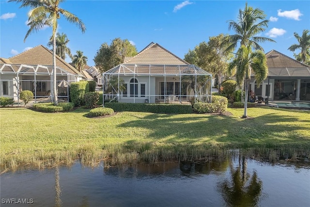 back of house with a water view, a lanai, a yard, and a tiled roof
