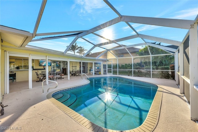 outdoor pool featuring glass enclosure and a patio area