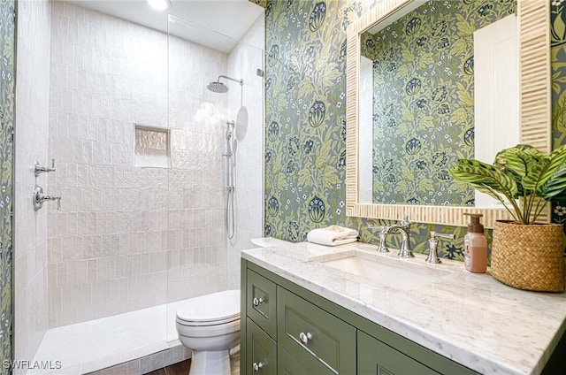 bathroom featuring vanity, tiled shower, and toilet