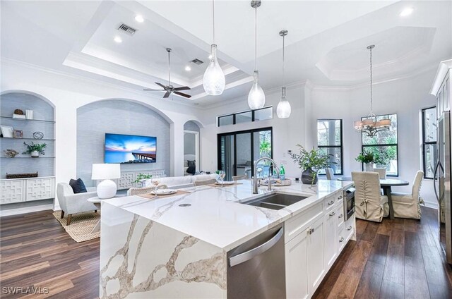 kitchen with sink, an island with sink, white cabinets, stainless steel dishwasher, and a raised ceiling