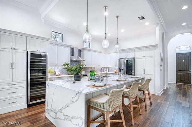 kitchen featuring a large island, stainless steel fridge, a breakfast bar, beverage cooler, and wall chimney exhaust hood