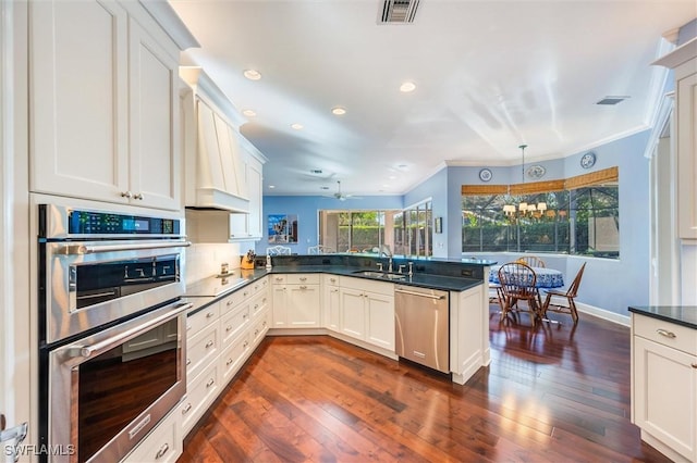 kitchen featuring a sink, appliances with stainless steel finishes, visible vents, dark countertops, and a peninsula