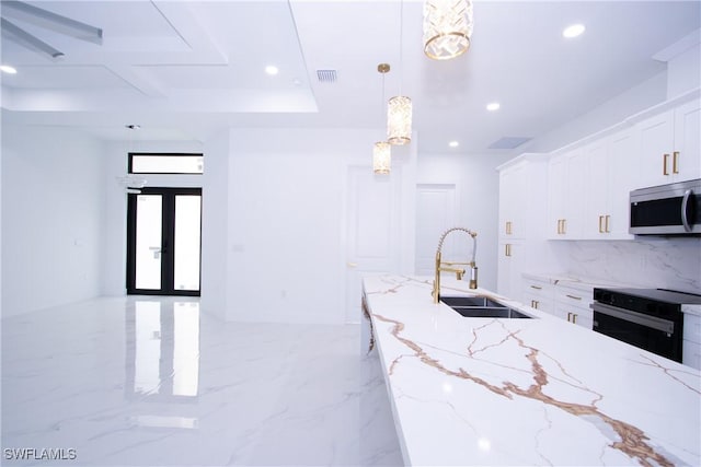 kitchen featuring sink, white cabinetry, light stone counters, pendant lighting, and oven