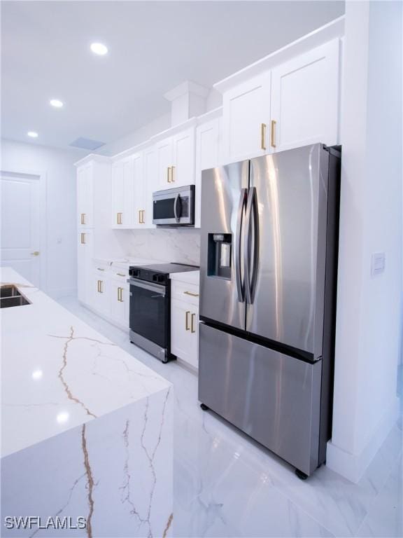 kitchen featuring light stone counters, stainless steel appliances, sink, and white cabinets