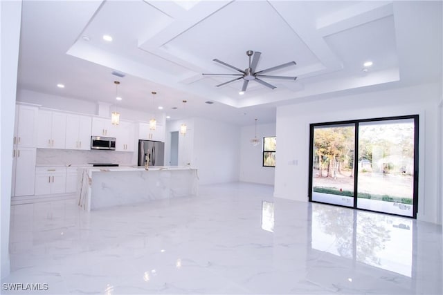 unfurnished living room featuring ceiling fan and a tray ceiling