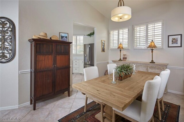 dining space with light tile patterned floors, lofted ceiling, and baseboards