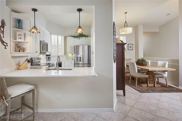 kitchen featuring sink, appliances with stainless steel finishes, white cabinetry, hanging light fixtures, and kitchen peninsula