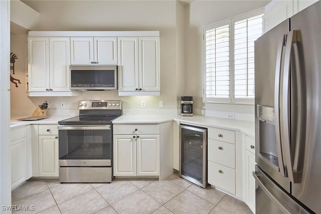 kitchen with stainless steel appliances, beverage cooler, light countertops, and white cabinetry
