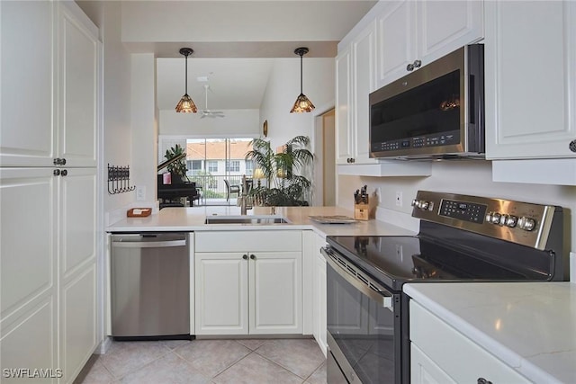 kitchen with hanging light fixtures, stainless steel appliances, and white cabinets