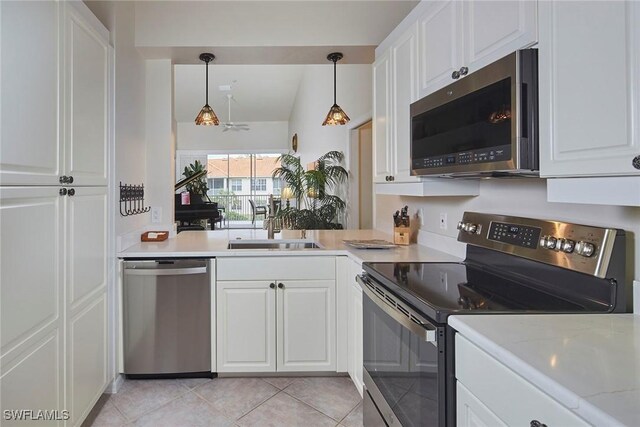 kitchen featuring stainless steel appliances, white cabinetry, vaulted ceiling, light tile patterned floors, and hanging light fixtures