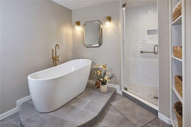bathroom with a shower stall, a freestanding tub, baseboards, and tile patterned flooring