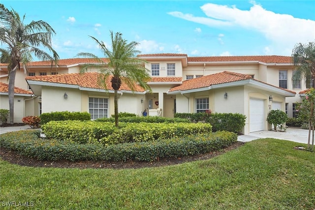 mediterranean / spanish-style house with an attached garage, driveway, stucco siding, a front lawn, and a tile roof