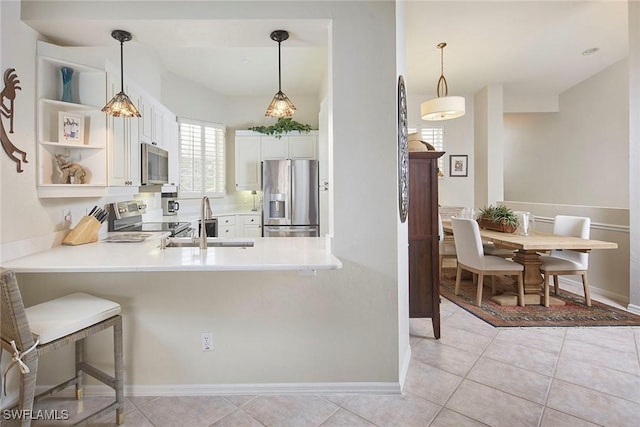 1033 Egrets Walk Cir Unit 203, Naples, FL 34108 - kitchen featuring appliances with stainless steel finishes, a sink, white cabinets, a peninsula, and light countertops