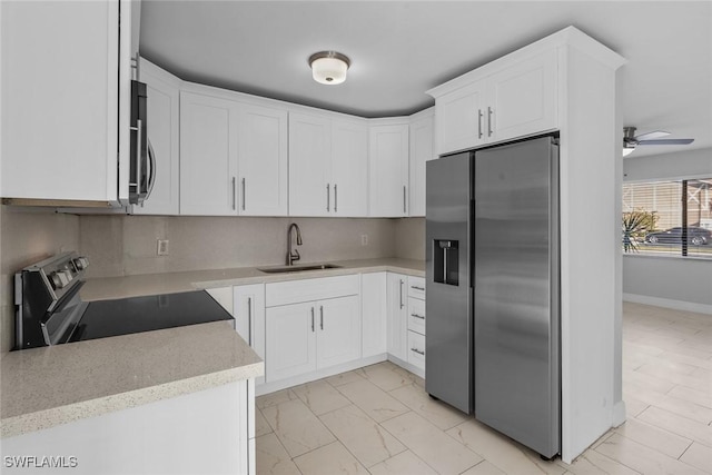 kitchen with sink, white cabinetry, appliances with stainless steel finishes, ceiling fan, and decorative backsplash