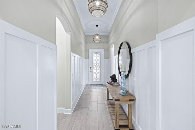 entryway featuring crown molding, wainscoting, and a decorative wall