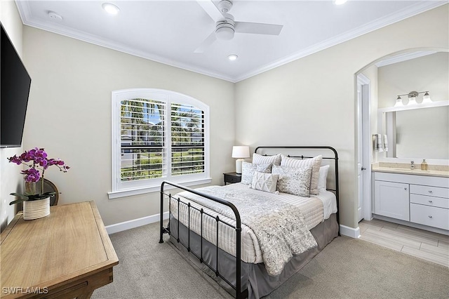 bedroom with ensuite bath, baseboards, crown molding, and light colored carpet