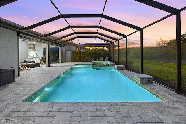 pool at dusk with a lanai, a yard, a pool with connected hot tub, and a patio