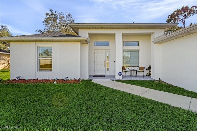 property entrance with a lawn and stucco siding