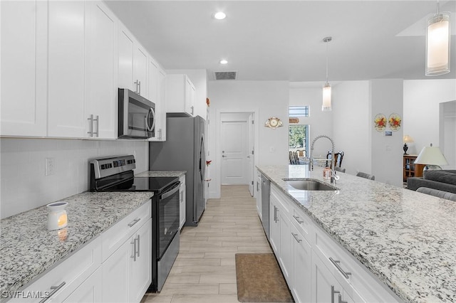 kitchen with stainless steel appliances, decorative light fixtures, sink, and white cabinets