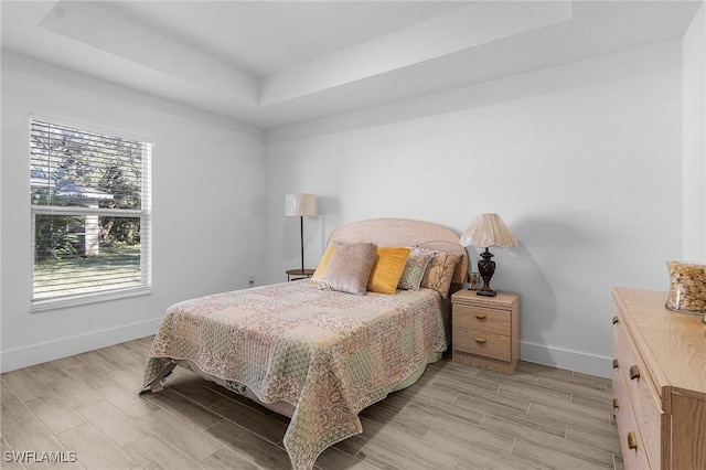 bedroom featuring a tray ceiling and light hardwood / wood-style flooring