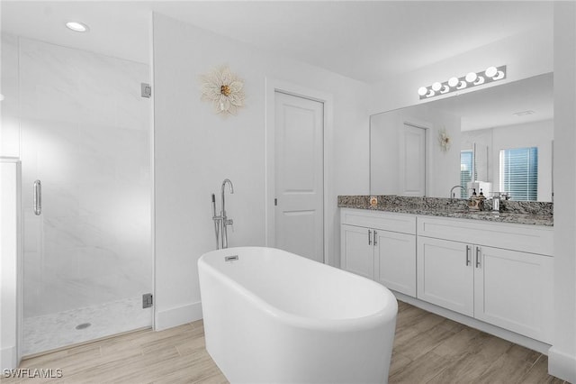 bathroom with wood-type flooring, shower with separate bathtub, and vanity