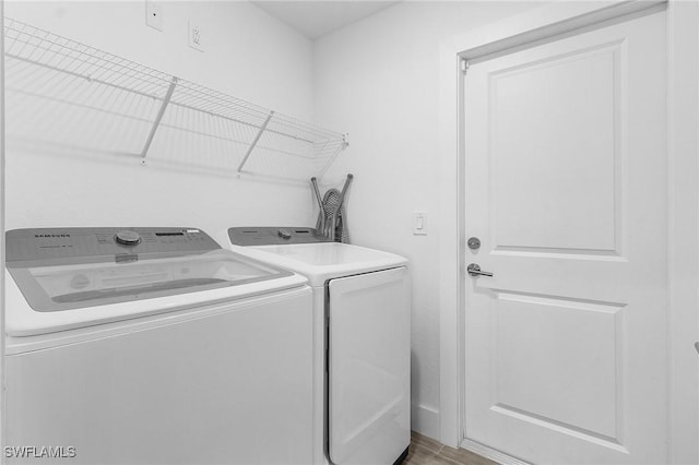 clothes washing area with hardwood / wood-style flooring and washing machine and clothes dryer